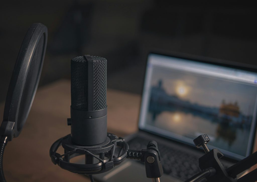 Close-up of a microphone with a pop filter and laptop, ideal for modern studio production